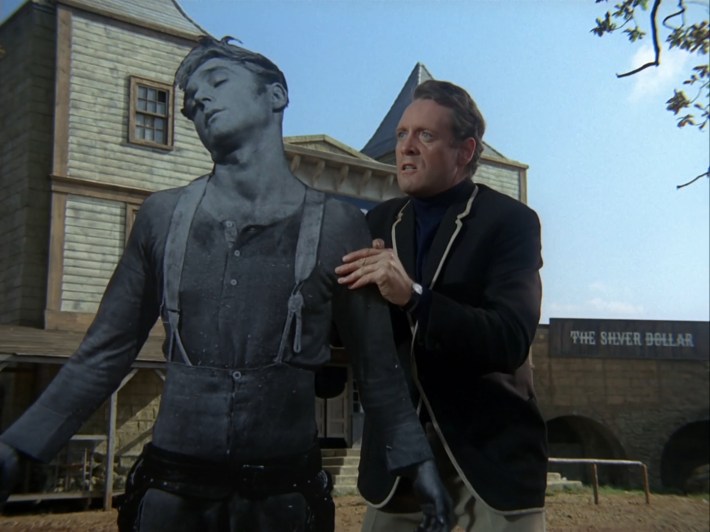 Six holds up a cardboard cut-out of Eight