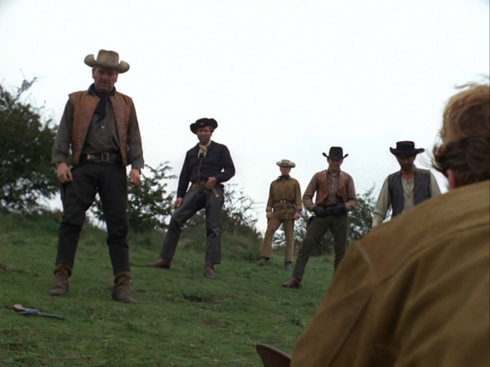 A number of men face off on a grassy hill