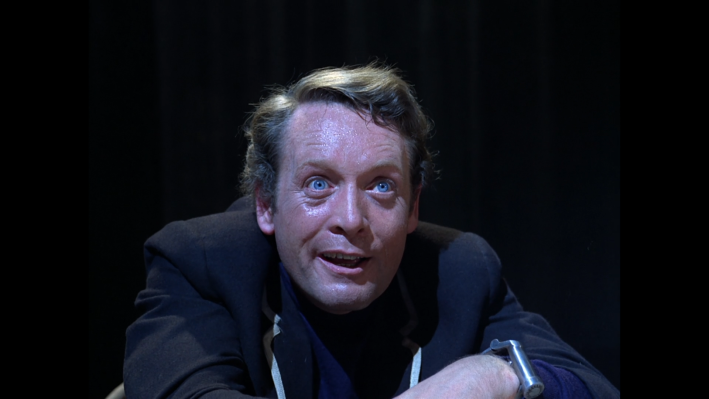 A tired man, Number Six, against a black background.