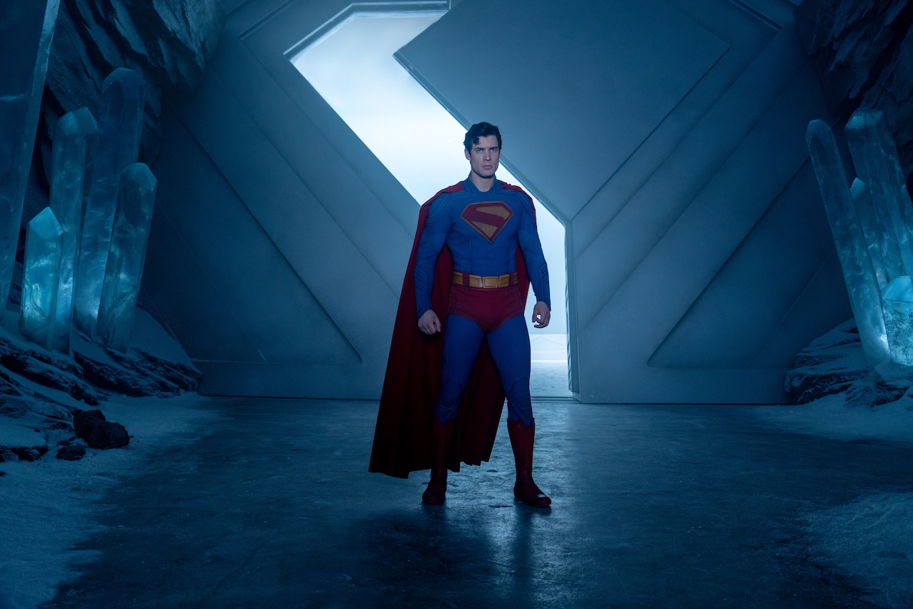 Superman standing in a dark room.
