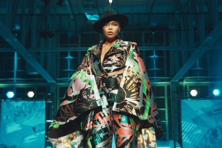 Model in hat and cape and pants made of crazy fabric