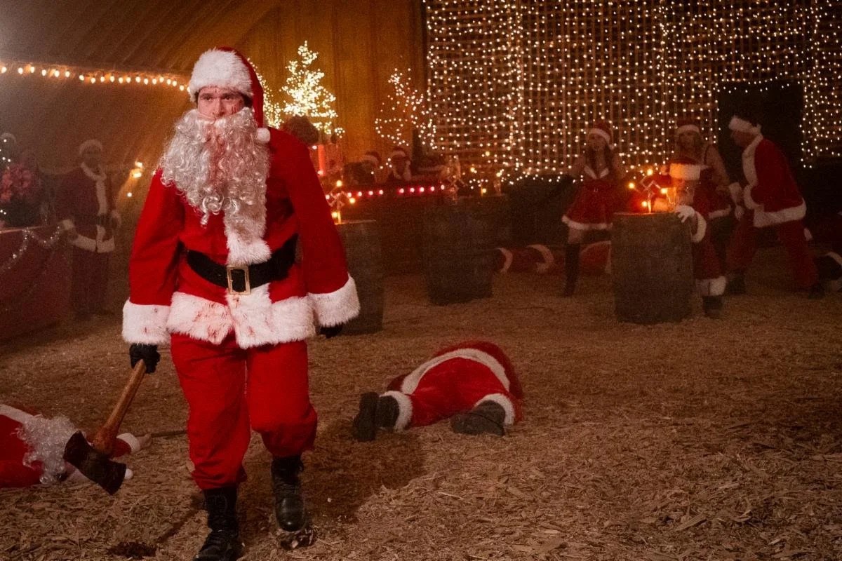 Santa with bloody beard walking through field with axe.