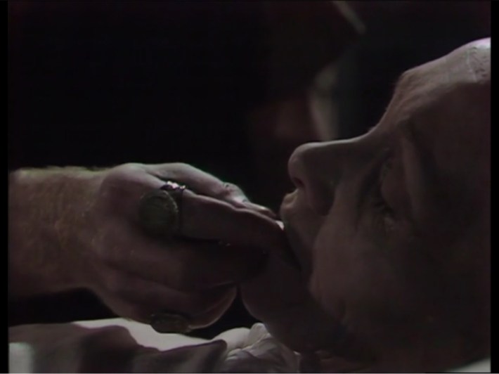 Claudius placing coin in Livia's mouth