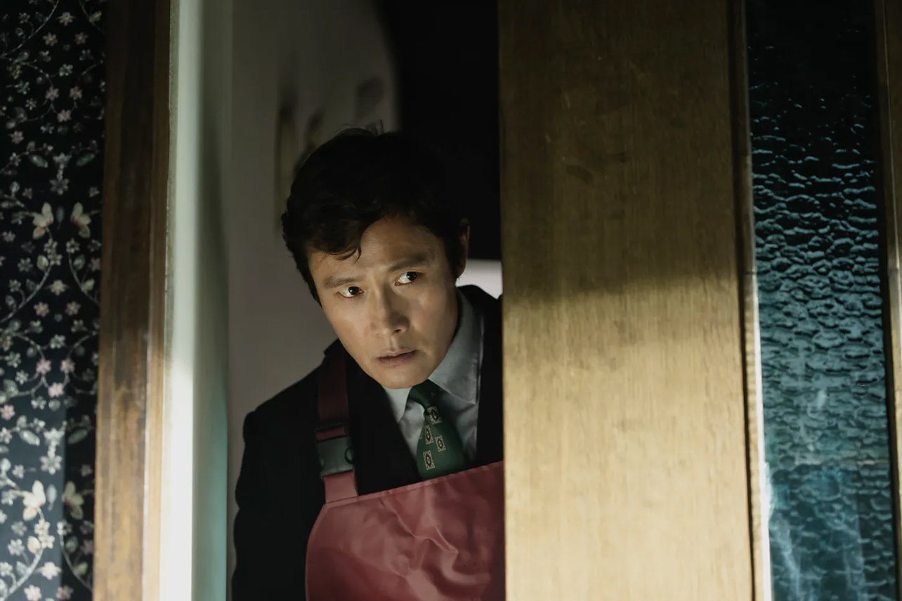 Man in apron looking through door