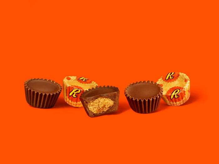 unwrapped Reeses peanut butter cups on orange background