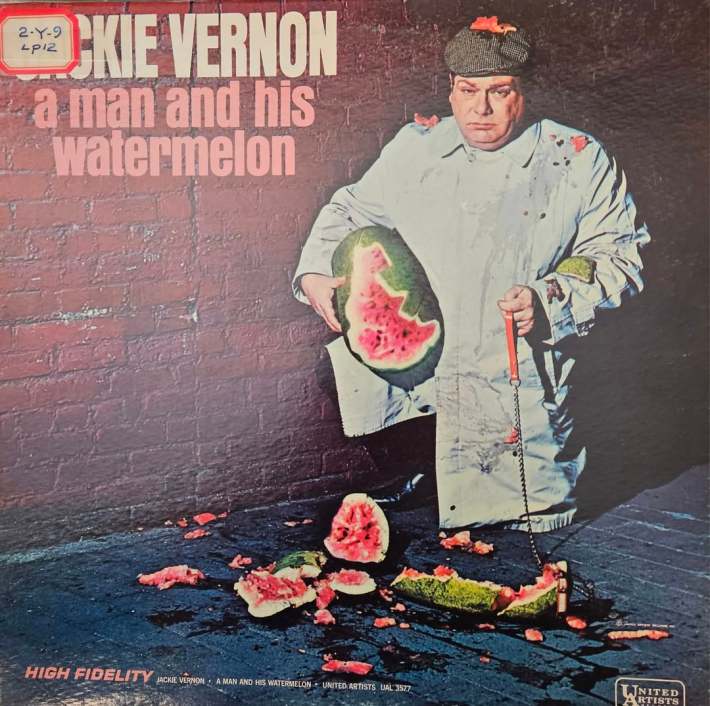 A record album cover titled "Jackie Vernon: A Man and his Watermelon". A large man in a smock holds a shattered watermelon in an alley."