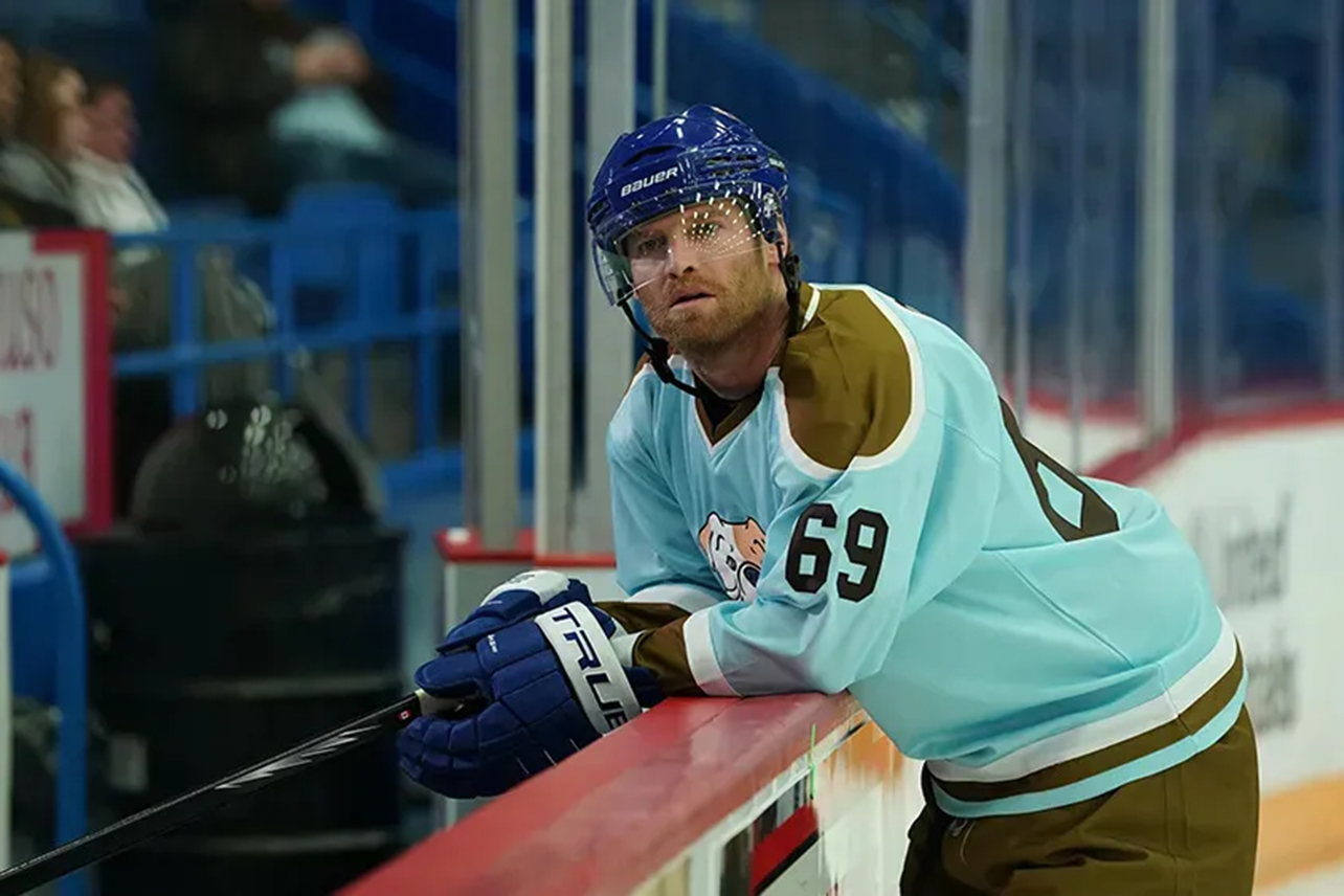 Hockey player leaning against side of rink