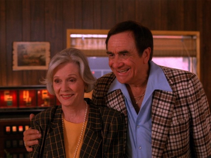 Couple, man with arm around woman, man looks cheesy