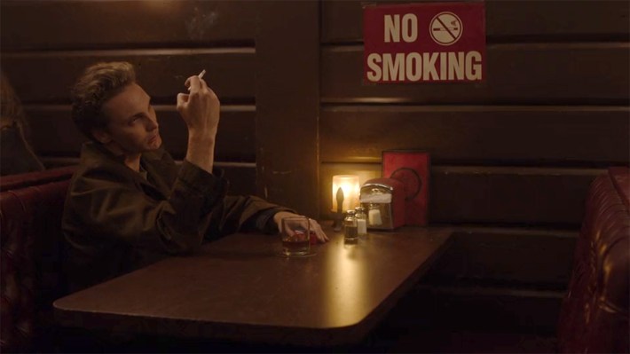 Man smoking in front of no smoking sign